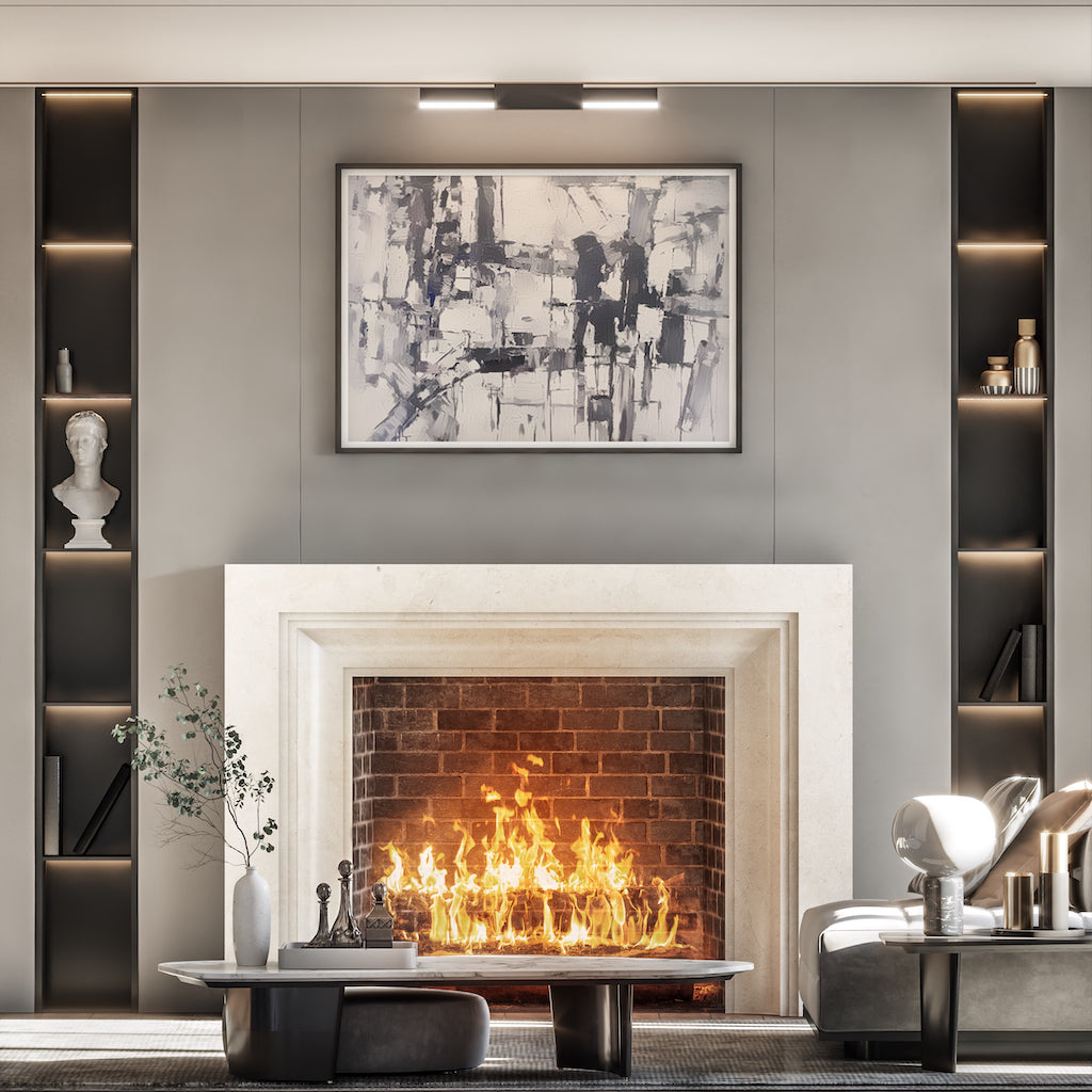 white marble fireplace with a lit fire on a grey wall with a picture frame above
