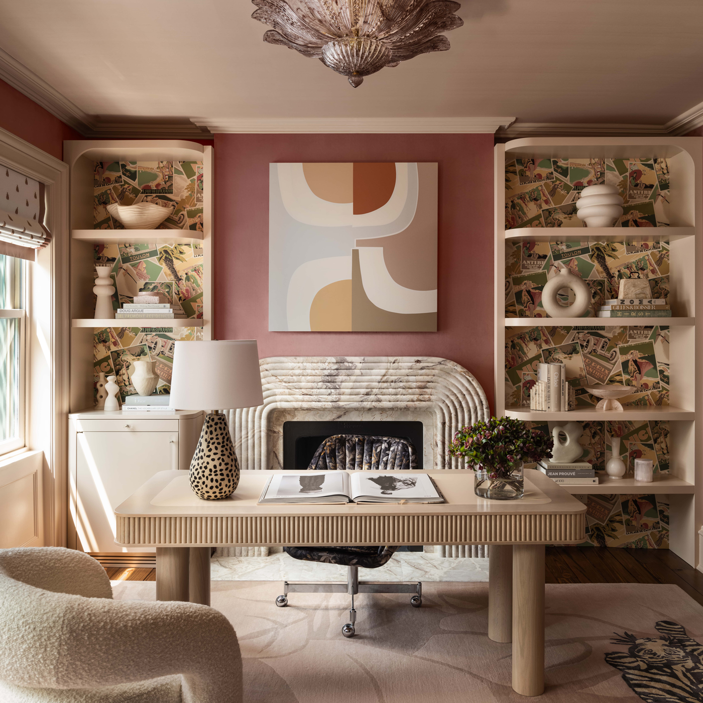 A pink office in bright afternoon light with a cream furniture and a white marble fireplace
