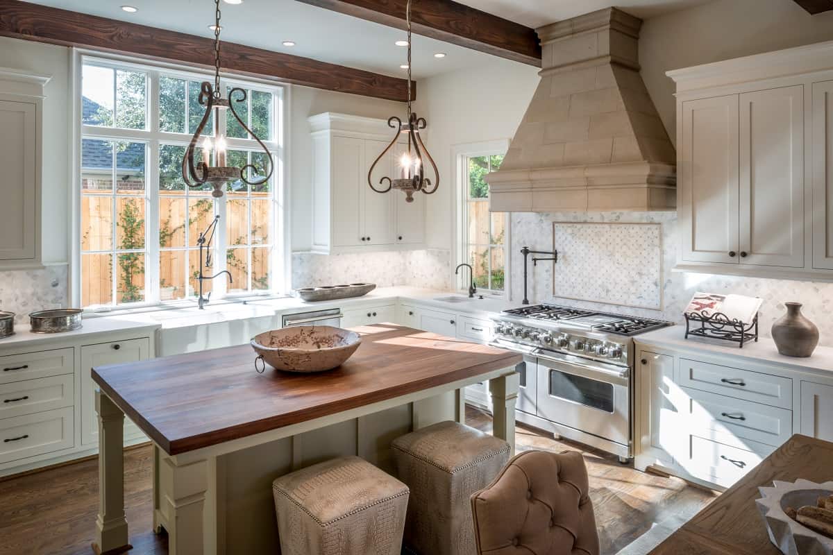 a modern kitchen with a mosaic backsplash and a stainless steel stove with a limestone hood