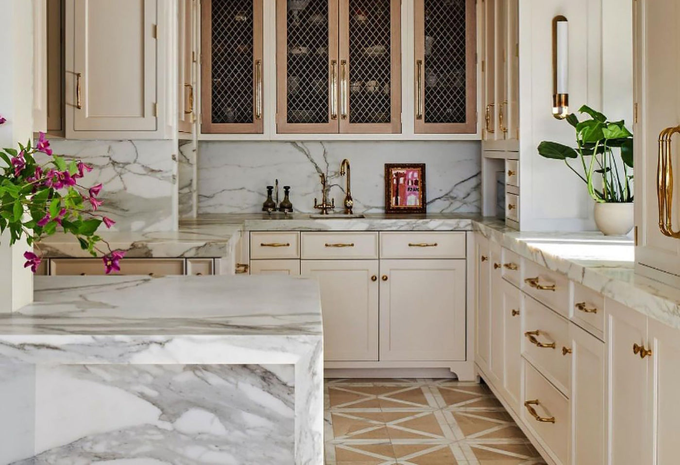 A kitchen with a white marble island and counter backsplash. The floor is a white and orange marble mosaic.