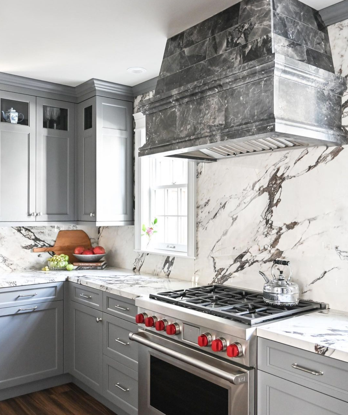 white marble walls and a grey marble kitchen hood over the stove