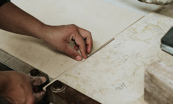 A close-up of a hand aligning sheets of material on a workbench, showcasing intricate details and craftsmanship in process.