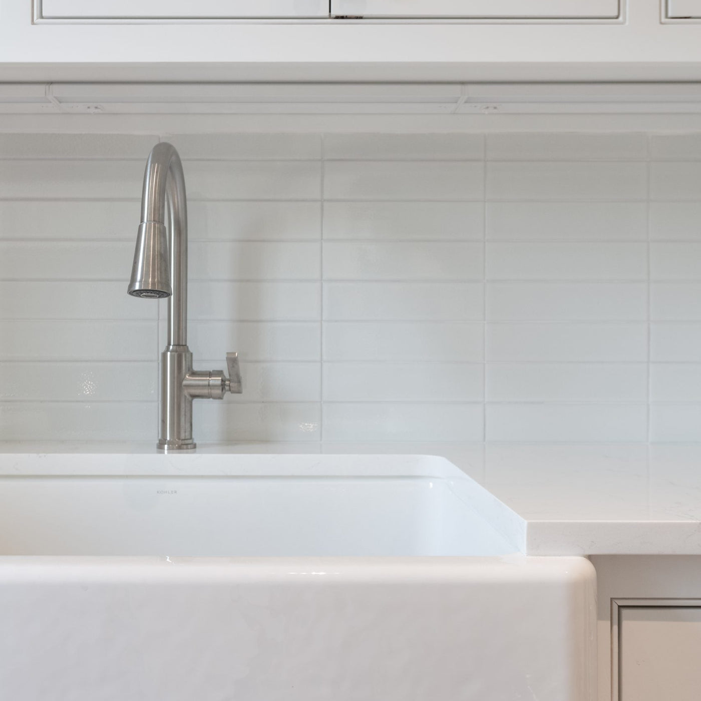 close up of a kitchen skink with white cabinets above 