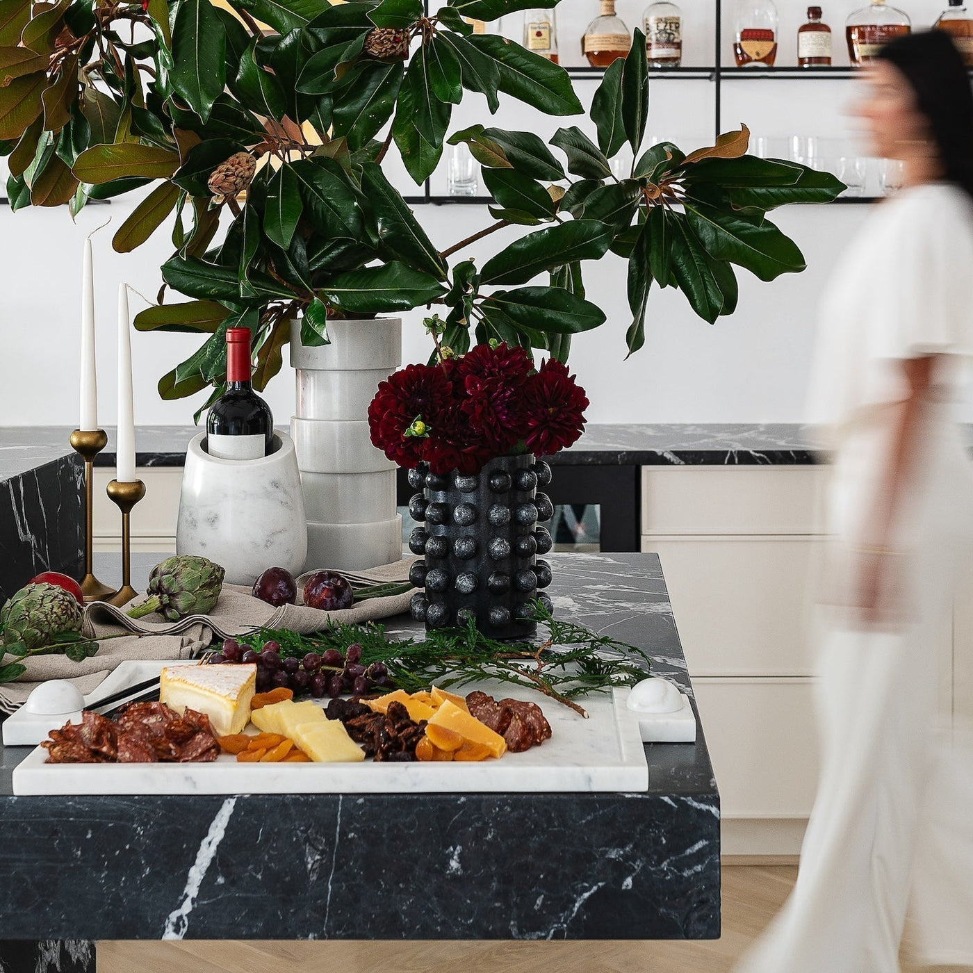 woman walking past a black marble table with food on it
