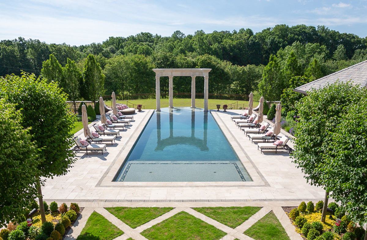 a big pool with tanning chairs on moth sides