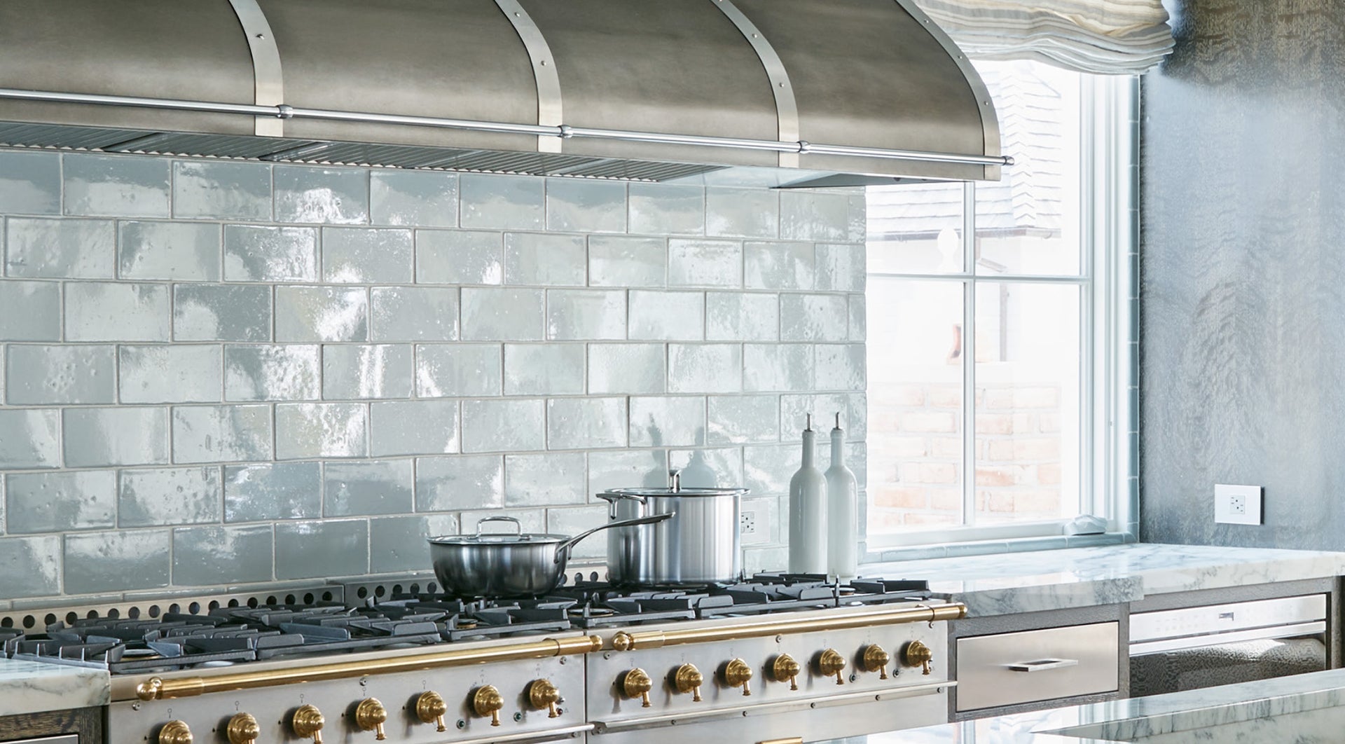 Modern kitchen with stainless steel range hood and white tiled backsplash - Desktop View