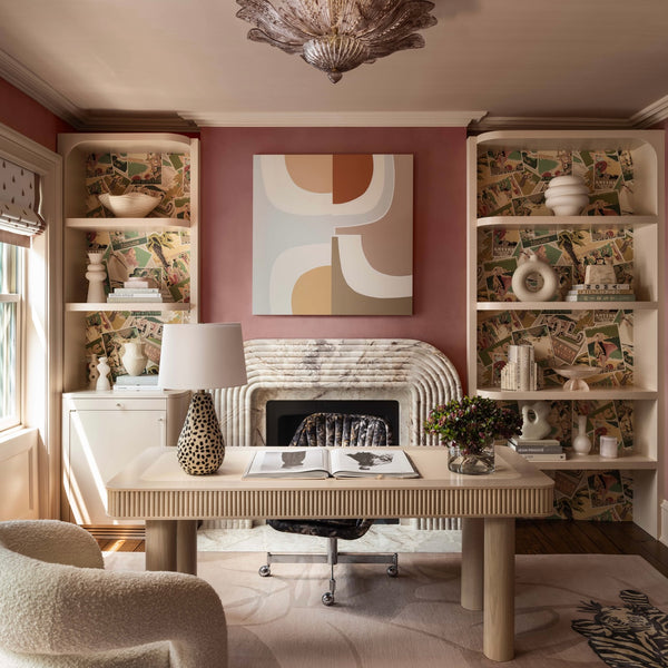 A pink home office with cream and white furniture and a breccia fiore marble fireplace